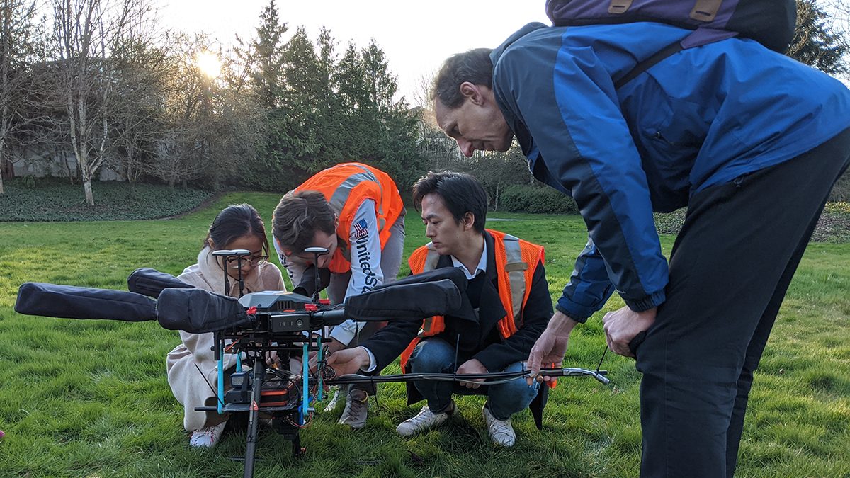 students and teacher look at a drone together