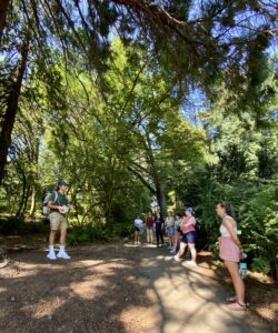 Photo of Owen Oliver and EarthLab summer interns standing under a large tree during the Indigenous Walking Tour on the UW Seattle campus. 