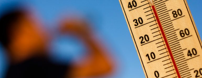 Image of thermometer in the foreground and a person drinking water in the background