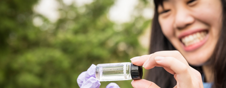 Image of person on UW Bothell campus collecting wetland water samples.