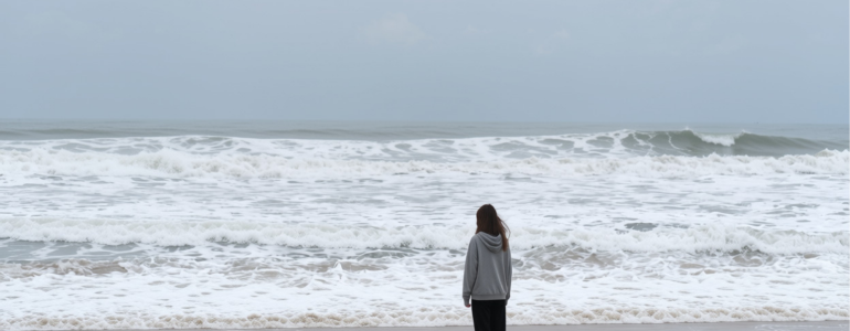Image of lone teenager staring at ocean waves